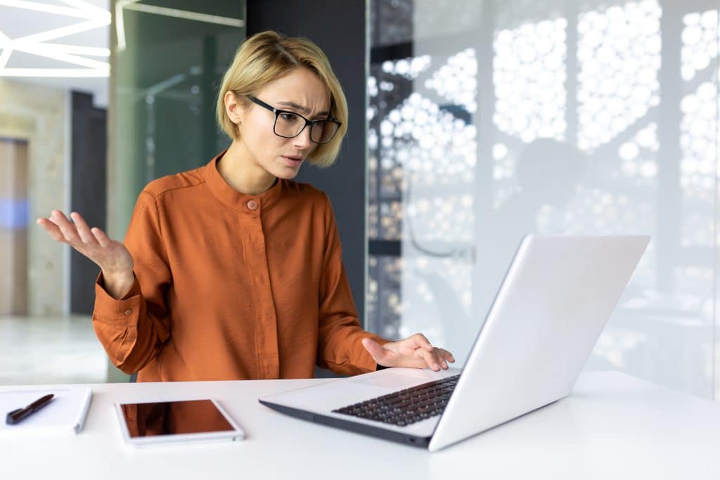Dissatisfied and upset woman at workplace looking at laptop screen, business woman received error and refusal of online banking transaction, female worker disappointed inside office\.